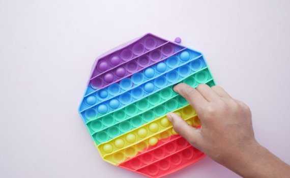 Child presses a rainbow popper fidget toy