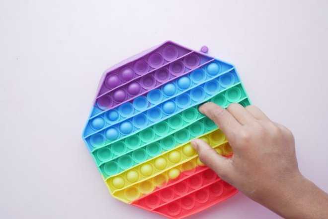 Child presses a rainbow popper fidget toy